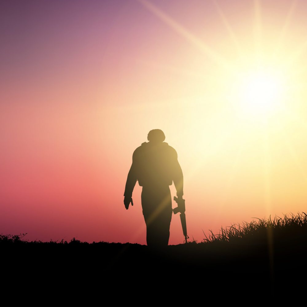 Silhouette of a soldier walking against a sunset sky