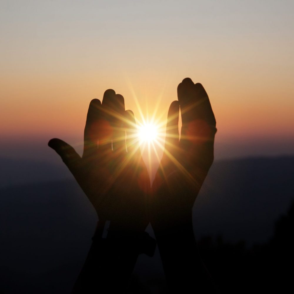 Faith of christian concept: Spiritual prayer hands over sun shine with blurred beautiful sunset background